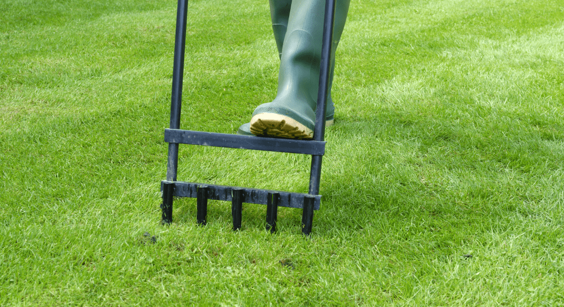 Person wearing green boots using a lawn aerator on grass. The Ultimate Guide to Lawn Aeration in Clarksville, TN 