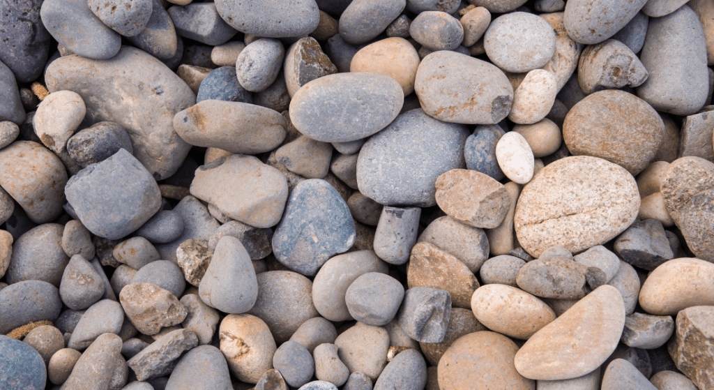 A collection of smooth, multicolored stones closely packed together. how much is landscape rock installation.