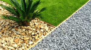 A small palm tree surrounded by tan pebbles is next to a patch of green grass. Adjacent is a section covered with gray gravel. how much is landscape rock installation.